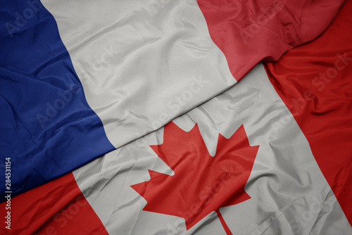 waving colorful flag of canada and national flag of france.