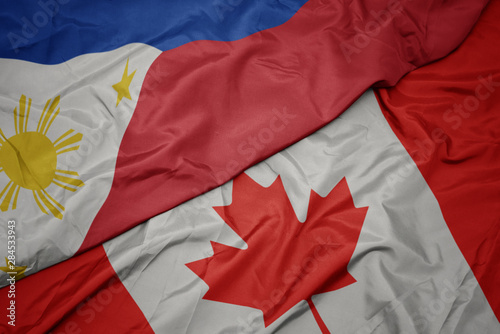 waving colorful flag of canada and national flag of philippines.