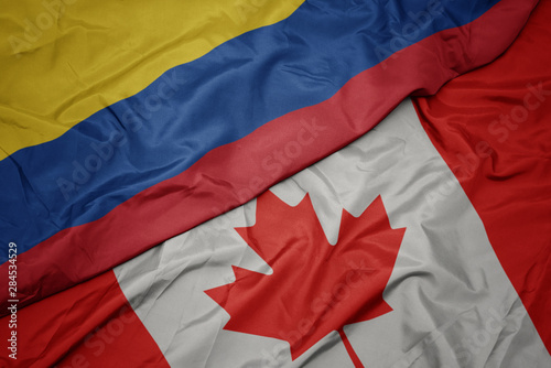 waving colorful flag of canada and national flag of colombia.