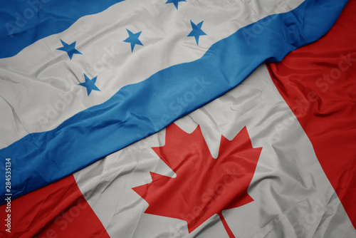 waving colorful flag of canada and national flag of honduras.