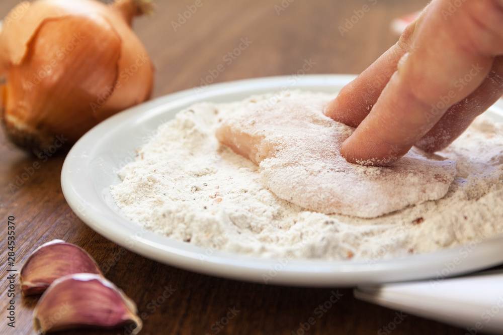 Breading of raw chicken. Hand pushing into flour with spices. close up shot. onion garlic Breading of raw chicken. Hand pushing into flour with spices. close up shot. onion garlic
