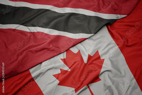 waving colorful flag of canada and national flag of trinidad and tobago.