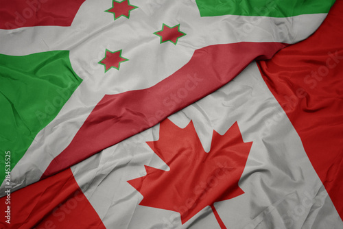 waving colorful flag of canada and national flag of burundi.