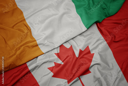 waving colorful flag of canada and national flag of cote divoire.