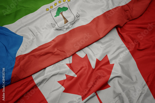 waving colorful flag of canada and national flag of equatorial guinea.