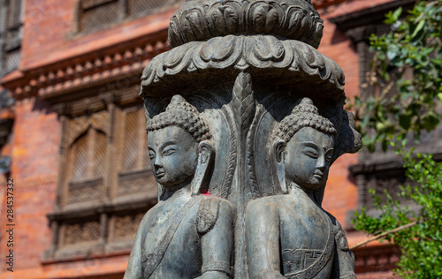 .close up of a Buddhist statue with a blurred wooden balcony in the background photo