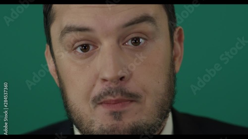 Close-up of young man dubious swindler talking foolish things on camera trying to deceive people. Political lier. Shot with green screen background photo