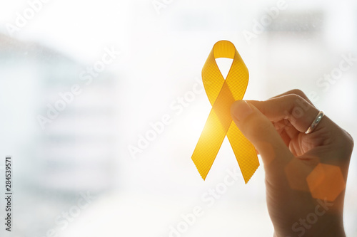 Suicide prevention and Childhood Cancer Awareness, Yellow Ribbon on wooden background  for supporting people living and illness. children Healthcare and World cancer day concept photo