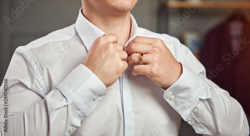 businessman dresses white shirt, male hands closeup,groom getting ready in the morning before wedding ceremony