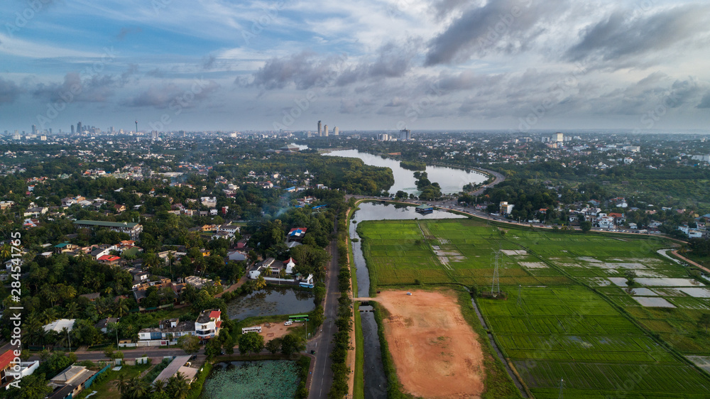 An Ariel view of an urban paddy field with a walking track running around it in sri lanka