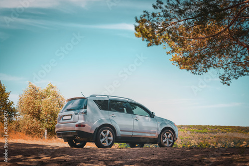 Silver SUV in the autumn forest off road photo