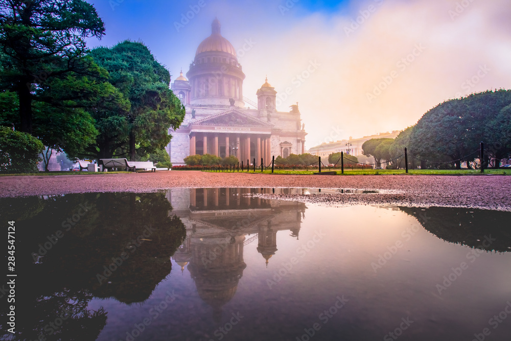 Obraz premium Russia. St. Petersburg on a cloudy day. St. Isaac's Cathedral in the fog. Reflection of the Cathedral and trees in a puddle. Business card of St. Petersburg. Panorama Of St. Petersburg