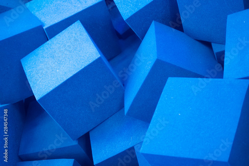 Randomly lying blue foam cubes. Graphic concept. Blue foam cut into cubes. Blue background. Volumetric image. Styrofoam