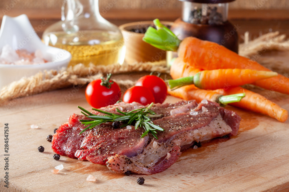 Beef steak with vegetables and spices on a cutting board
