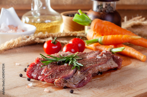 Beef steak with vegetables and spices on a cutting board