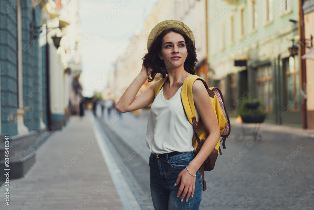 Smiling woman traveler with a backpack. On the street of an old town. With a beautiful architecture on the background.