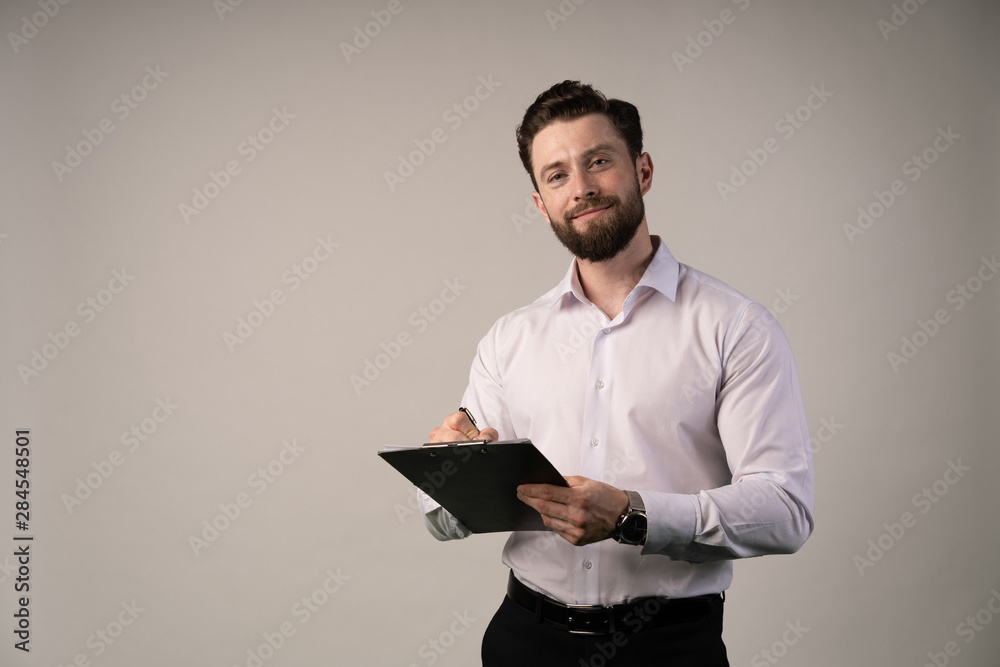 Middle age, 30-40s smiling businessman signing official contract or filling business document with a pen, working in modern office with cup of coffee , close up. Middle age, 30-40s smiling businessman signing official contract or filling business document with a pen, working in modern office with cup of coffee , close up.
