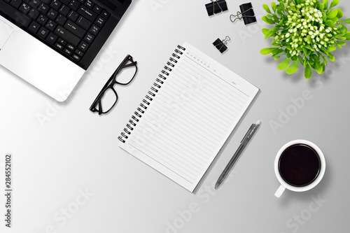 Office desk or education desk with laptop  Pen  Notebook  paper clip  glasses  Flower vase and coffee  top view 