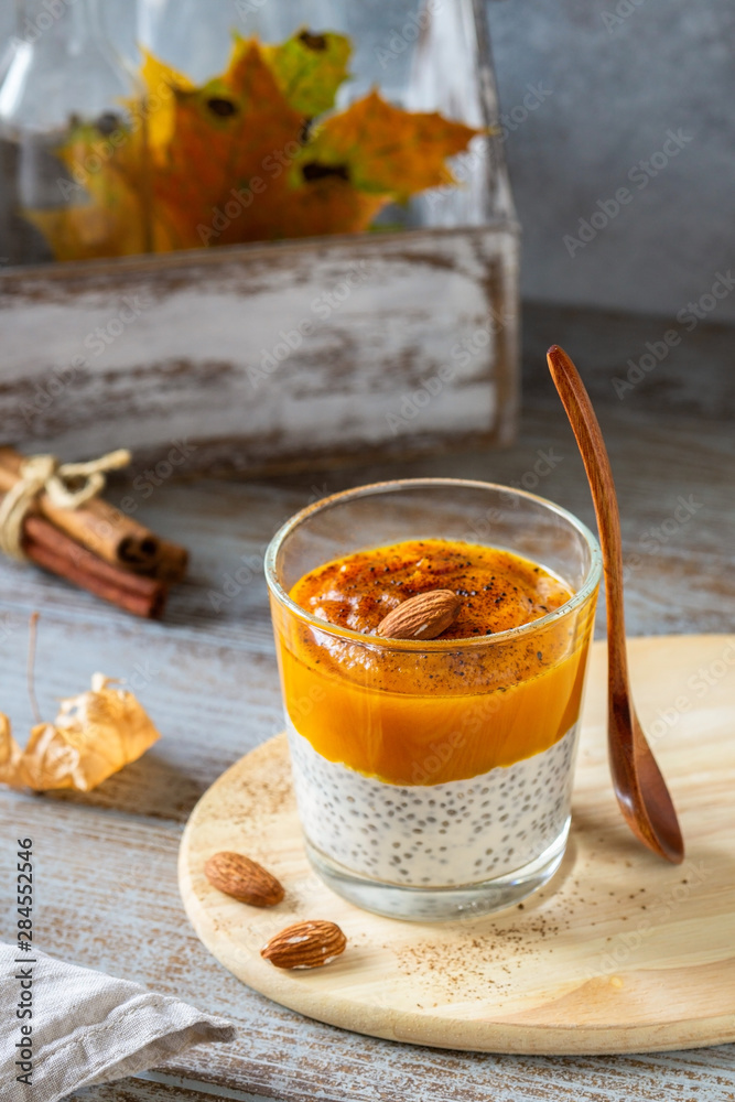 Healthy breakfast - Chia seeds pudding with spicy pumpkin puree and almonds on gray wooden rustic table. Health care, fitness, diet, super food concept. Healthy breakfast - Chia seeds pudding with spicy pumpkin puree and almonds on gray wooden rustic table. Health care, fitness, diet, super food concept.