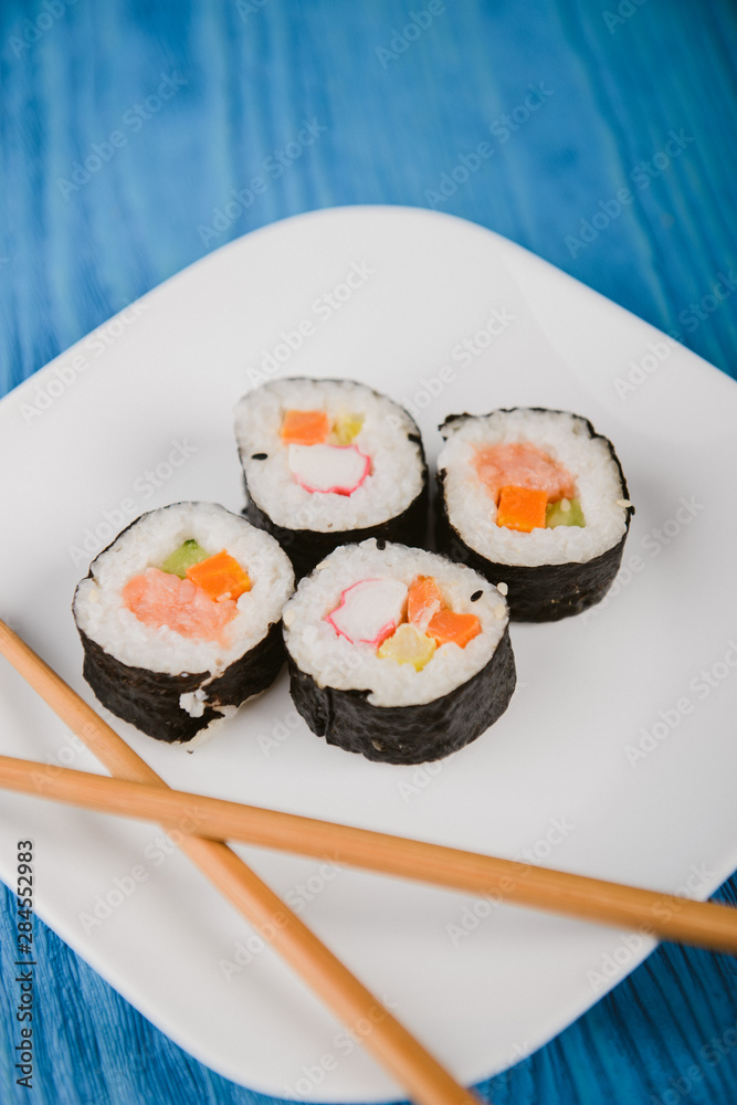 sushi roll lying on white plate. Blue background sushi roll lying on white plate. Blue background