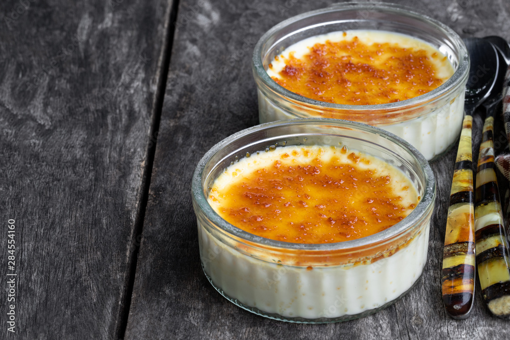 Closeup of creme brulee in glass jars on rustic wooden table