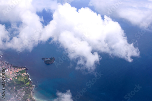 Beautiful view of the sea and the coast of the island of San Miguel from the porthole of the plane. White clouds over the atlantic ocean. Azores, Portugal. © Лариса Люндовская