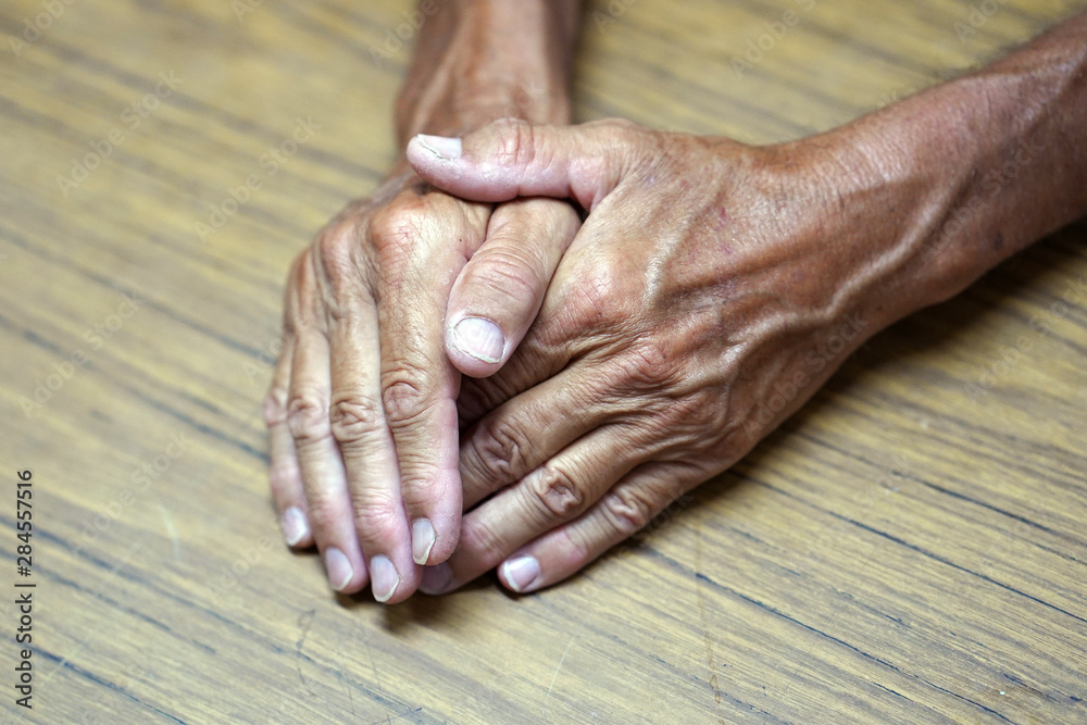 Fototapeta premium Wrinkled hands of old man of on the table. Handicapped hand. Side view