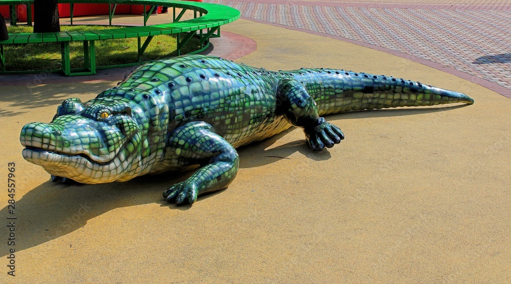 Fototapeta premium the figure of a crocodile near the Park bench