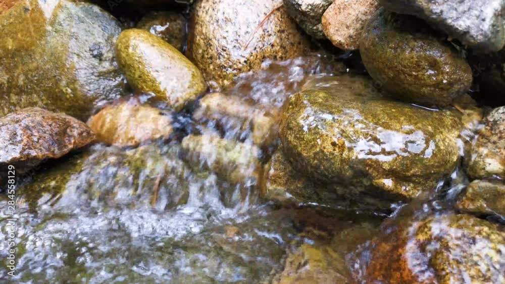 A water flows through the rocks, Closeup of rapids, Closeup of water flowing over rocks in small river in Malaysia A water flows through the rocks, Closeup of rapids, Closeup of water flowing over rocks in small river in Malaysia
