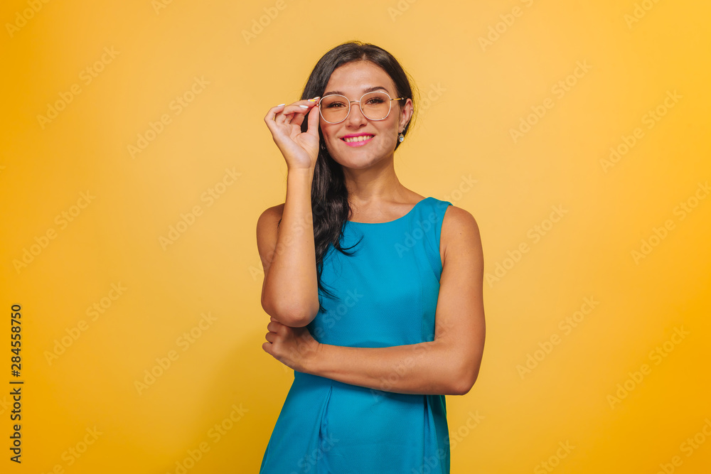 Girl on yellow background with glasses and blue dress