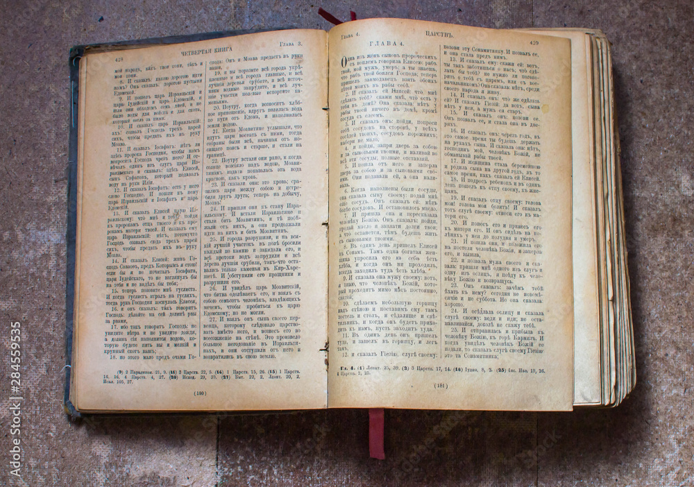 Obraz premium Old opened book with yellowed pages on a wooden table.