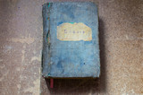 Old bible in a blue cloth cover on a wooden table.
