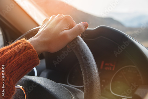 Fototapeta Close-up of a female hand in an orange sweater driving a car outside the city