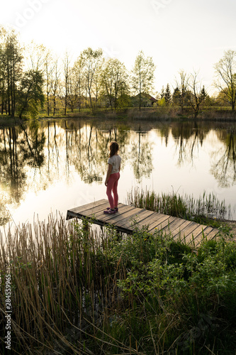 Girl standing by the lake watching sunrise in Poland