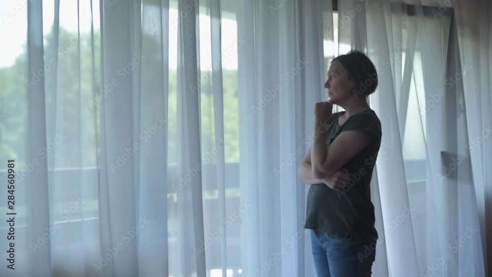 Sad worried woman standing alone by the window Sad worried woman standing alone by the window