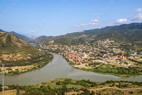 Confluence of the Mtkvari and Aragvi rivers viewed from above at Mtskheta - one of the oldest cities in Georgia - and view of the Svetitskhoveli Cathedral with mountains in background