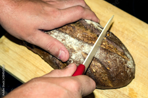 Man cut the craft rye bread, closeup