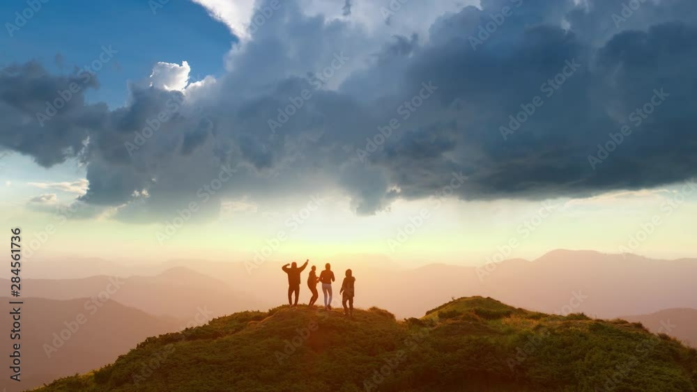 The four people dancing on the mountain with the beautiful view