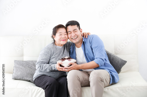 Asian Son give some present box to mother in living room smile and happy face in mother day
