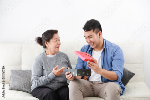 Asian Son give some present box to mother in living room smile and happy face in mother day
