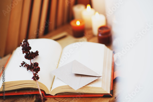  homeliness, hygge, candles, old books, diary and dried flowers on a wooden background, vintage