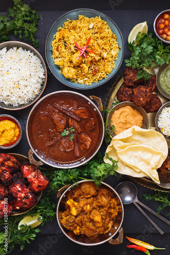 Indian dishes ready to eat featuring rogan josh, chicken tikka masala, biryani, kebabs, pasties, dips and naan bread, top view