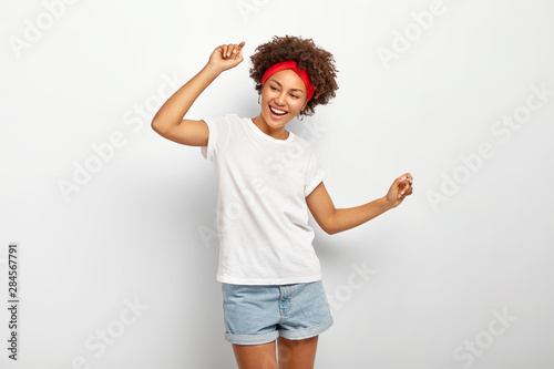 Принти на полотні Carefree pleased teenage girl has fun, dances joyfully with raised arms, being e