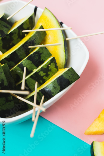 triangular slices of ice cream on a stick of ripe yellow watermelon in a plate