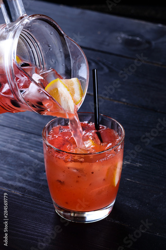 the process of preparing hamemade lemonade. pouring water into a glass photo