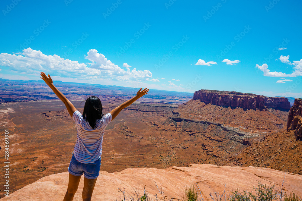 Woman standing at the top of a canyon at Canyonlands National Park in Utah during summer Woman standing at the top of a canyon at Canyonlands National Park in Utah during summer