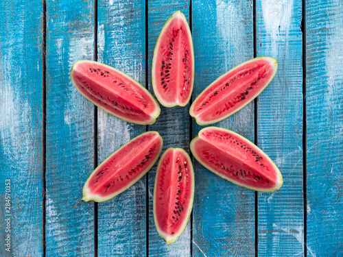 Large pieces of ripe watermelon on a blue wooden background.