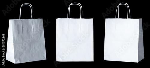 Set of new empty blank paper bag with handles without inscriptions and logos. Made from white kraft paper. Isolated on black background. photo