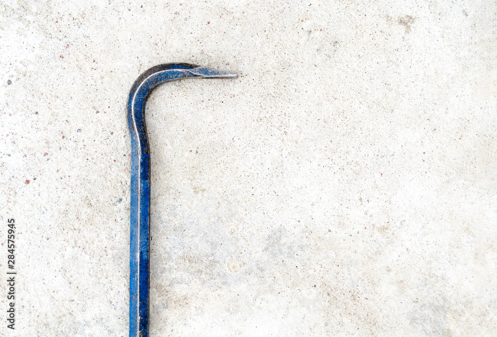 Metal crowbar lie in the left on the gray grunge concrete background