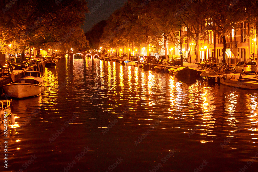 Night scene along a Canal with lights and boats in Amsterdam